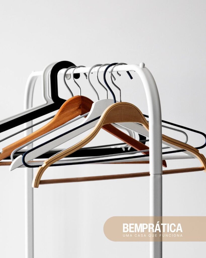 Cabides para roupas de metal e madeira pendurados em varão, mostrando diferentes modelos para escolher o melhor tipo de cabide